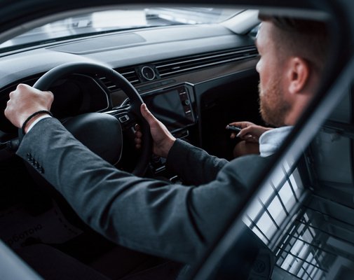 Going forward. Lovely successful couple trying new car in the automobile salon